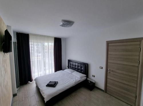 een slaapkamer met een bed en een groot raam bij Alezzi beach luxury Lidia apartment in Mamaia Nord – Năvodari