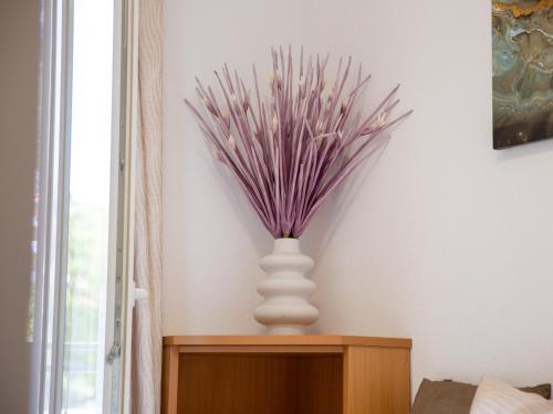 a white vase with purple flowers in it on a table at Villa Alesa Steva in Tučepi