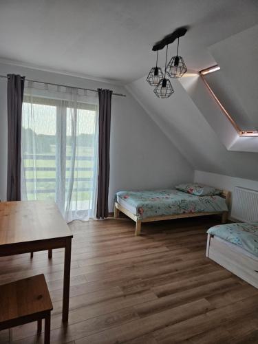 a room with two beds and a table and a window at Dom z Milkowej Polany 