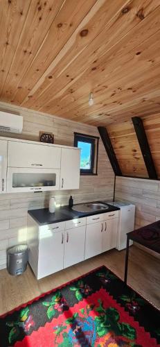 a kitchen with white cabinets and a wooden ceiling at Agin Konak in Gusinje