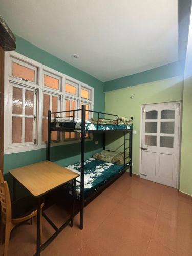 a room with two bunk beds and a table at ZuZu - A Travellers Hostel in Shimla