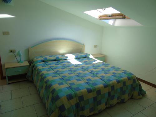 ビビオーネにあるBibione Vacanzeのベッドルーム1室(青と黄色の毛布付きのベッド1台付)