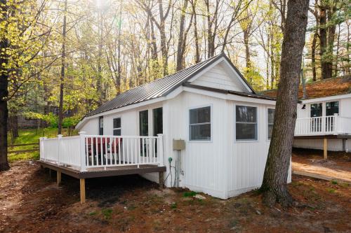 a white cabin in the woods with a tree at Arbutus Lakeview-Fishing-Pet Friendly-Near TC! in Traverse City