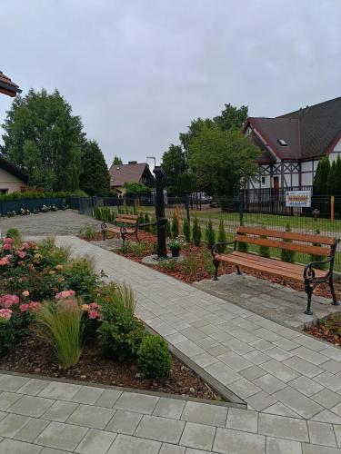 two park benches in a park with flowers at Willa Róż in Rusinowo
