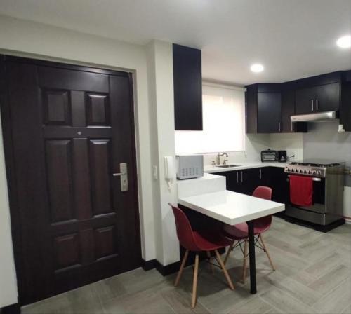 a kitchen with black cabinets and a white table and chairs at Departamento Sector de la Embajada Americana in Quito