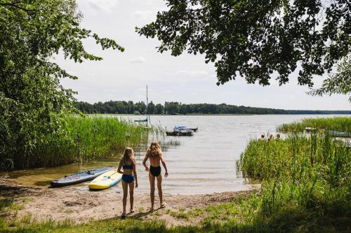two girls in bathing suits standing on the shore of a lake at Murawki Dom Blisko Jeziora in Urowo