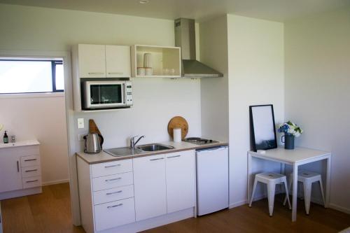 eine kleine Küche mit Spüle und Mikrowelle in der Unterkunft Wainui Beach studio - 2 minutes walk to beach in Gisborne