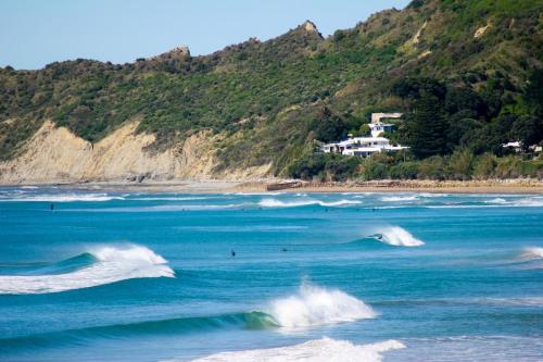 eine Gruppe von Menschen, die Wellen im Ozean reiten in der Unterkunft Wainui Beach studio - 2 minutes walk to beach in Gisborne