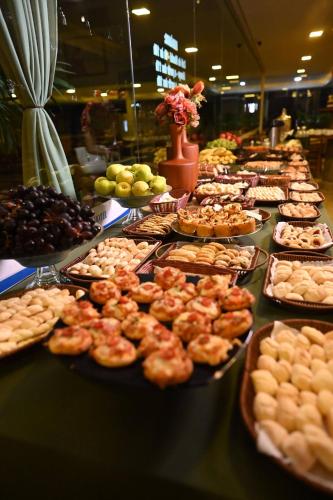 un buffet pieno di diversi tipi di cibo su piatti di Paracatu Plaza Hotel a Paracatu
