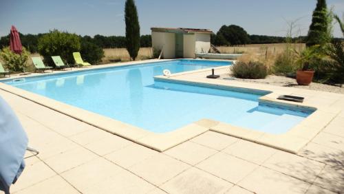 une grande piscine avec de l'eau bleue dans l'établissement La Petite Grange gîte climatisé plain-pied 3 chambres 5 personnes parking WIFI piscine chauffée animaux acceptés, à Lorignac