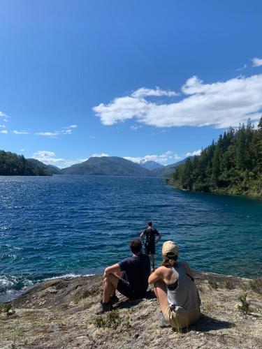 three people sitting on the shore of a lake at Refugio de Montaña Patagonia, pesca, trekking, miradores in Llanada Grande