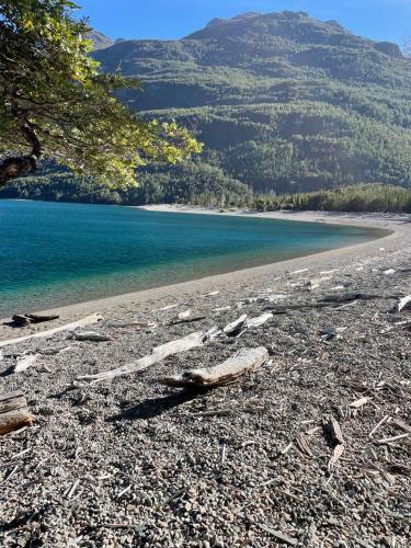 a beach with rocks and water and a mountain at Refugio de Montaña Patagonia, pesca, trekking, miradores in Llanada Grande