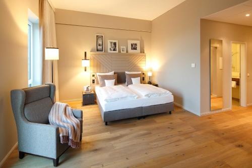 a bedroom with a bed and a chair at Romantik Hotel Kieler Kaufmann in Kiel
