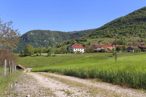 a dirt road in a field with a house in the background at Goute la vie in Marchamp