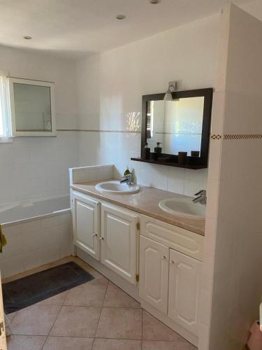 un bagno con un lavandino, uno specchio e una vasca di Villa spacieuse avec piscine privee a 150 m de la plage Calvi centre a Calvi