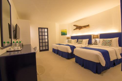 a hotel room with three beds and a television at GT Hotel Boracay in Boracay