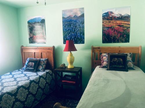 a bedroom with two beds and paintings on the wall at Sequoia Forest Retreat in Badger