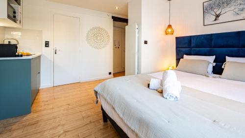 une chambre avec un grand lit blanc avec une tête de lit bleue dans l'établissement Sous le chêne bleu - Appartement Cosy au cœur de Dijon, à Dijon