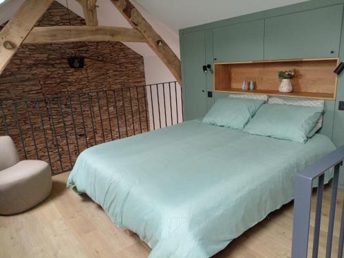 une chambre avec un grand lit et un mur de briques dans l'établissement gite paisible à la ferme, à Sainte-Honorine-de-Ducy