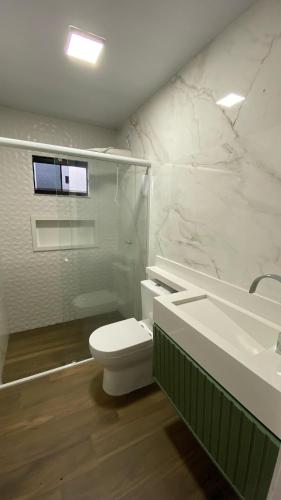 a white bathroom with a toilet and a sink at Casa de 3 quartos com piscina in Laranjeiras do Sul