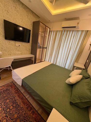 a bedroom with a bed and a desk and a television at The Crown in Greater Noida