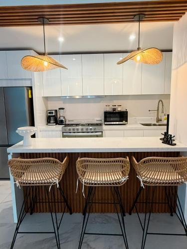 a kitchen with a counter with two stools at Apartamento 3 Recamaras en MAREA Los Cabos Playa Médano CSL in Cabo San Lucas