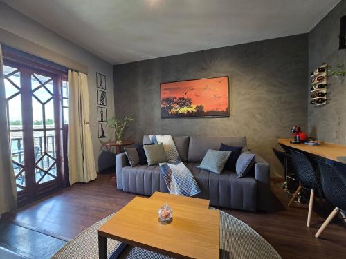 a living room with a couch and a table at Flat Completo - Piscina aquecida e vista p/ Serra in Campos do Jordão