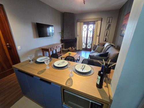 a kitchen with a table with plates and wine glasses at Flat Completo - Piscina aquecida e vista p/ Serra in Campos do Jordão