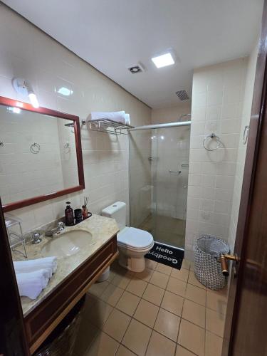 a bathroom with a toilet and a sink and a shower at Flat Completo - Piscina aquecida e vista p/ Serra in Campos do Jordão
