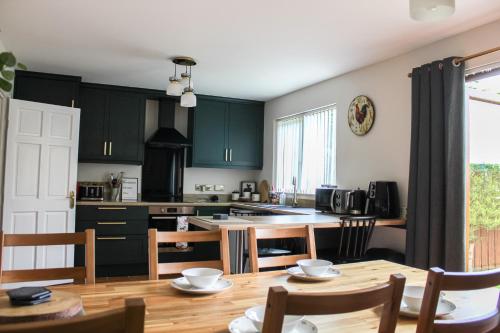 a kitchen with green cabinets and a wooden table at Whitepark Cottage - your home away from home in Ballycastle