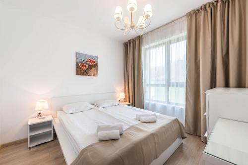 a white bedroom with a large bed and a window at Copacabacum Sea View in Varna City