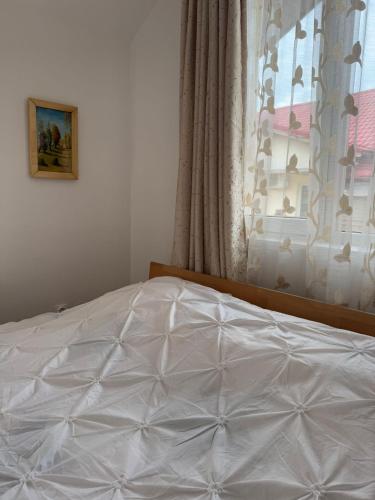 a white bed in a bedroom with a window at The Urban Hero Appartment in Floreşti