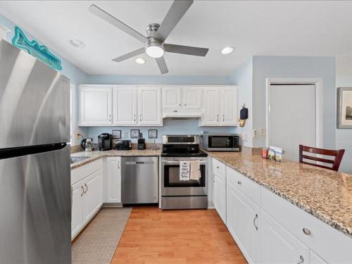 a kitchen with white cabinets and a stainless steel refrigerator at Seabreeze village 5 in Dewey Beach