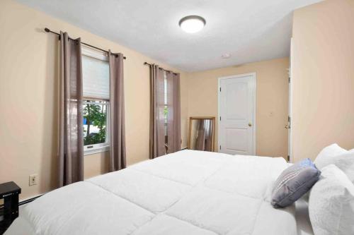 a large white bed in a bedroom with a window at Lovely Downtown Oasis Near Hospitals, Colleges, and Beaches in Amesbury