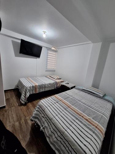 a bedroom with two beds and a flat screen tv at Dormitorio Doble in Lima