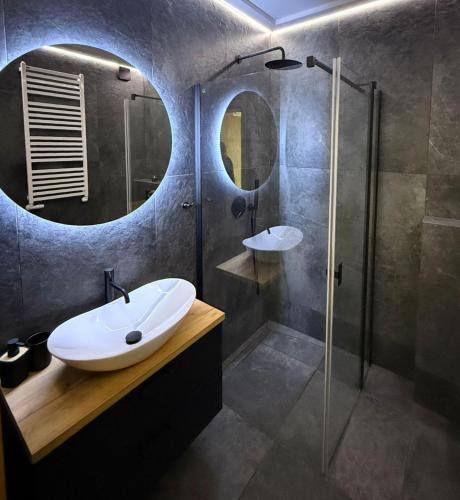 a bathroom with a sink and a shower with a mirror at Słoneczny Apartament Karpicko in Karpicko