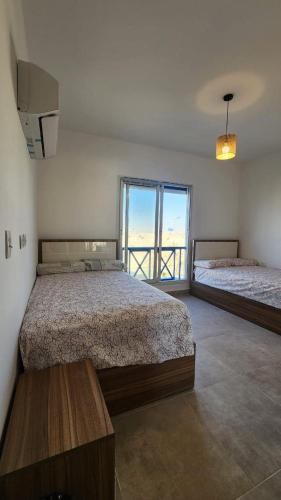 a bedroom with two beds and a large window at Boho Breez Mountain View Chalet in Ras Elhekma