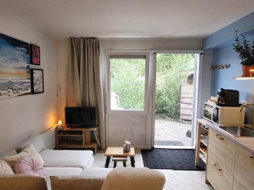 a living room with a white couch and a window at Appartement 2 met terras aan de tuin van Op de Roemte in Baflo