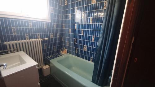 a blue tiled bathroom with a tub and a sink at House for 4 people with a breathtaking view in Plérin