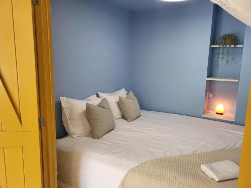 a bed with white pillows in a blue room at Appartement 2 met terras aan de tuin van Op de Roemte in Baflo