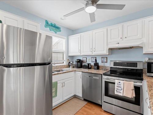 a kitchen with white cabinets and a stainless steel refrigerator at Seabreeze village 5 in Dewey Beach