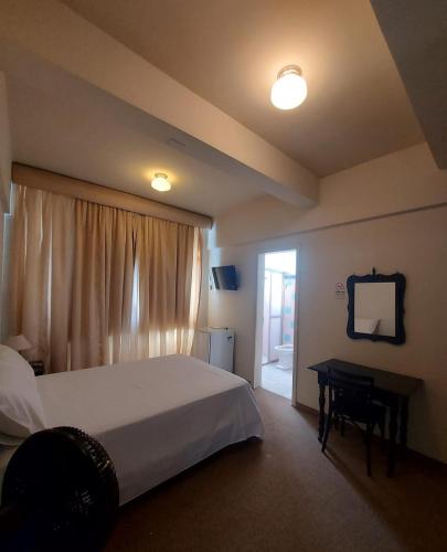 a bedroom with a bed and a desk and a window at Hotel Ponta Grossa São Marcos in Ponta Grossa