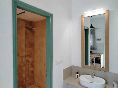 un bagno con lavandino e doccia con specchio di Oliveland Apartments a Kávos