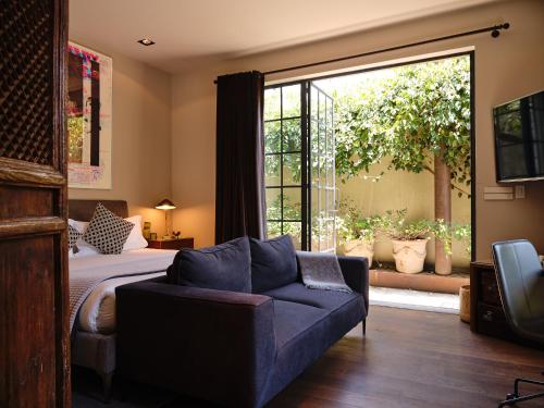 a bedroom with a bed and a couch and a window at Casa Seis Siete in Mexico City