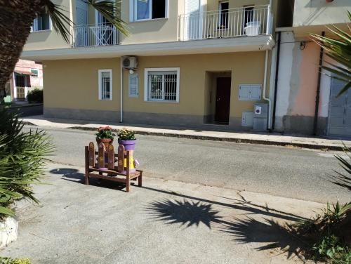 a street with a bench with flowers and a building at Agorà 1 in Parghelia