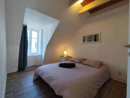 une chambre avec un grand lit blanc avec une fenêtre dans l'établissement El pisito Quimperois duplex 2 chambres coeur de ville, à Quimper
