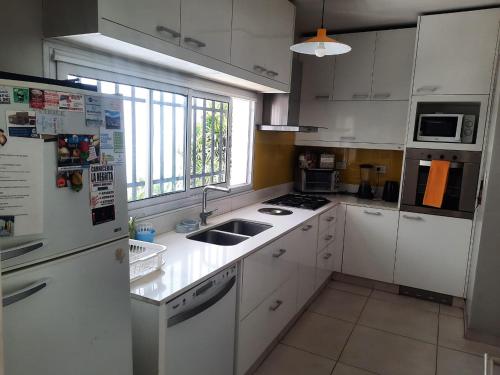 a white kitchen with a sink and a refrigerator at Spectacular House in Barrio Sur with a pool in San Miguel de Tucumán