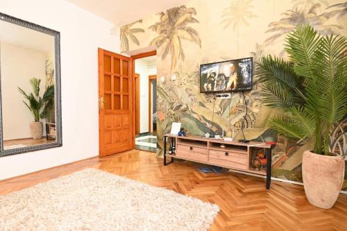 ein Wohnzimmer mit einem TV und einem Palmenmilch in der Unterkunft Apartmani Santa Barbara in Trebinje