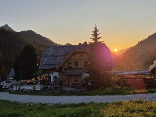 a house in the mountains with the sunset in the background at Ferienwohnung Johannes in Planneralm
