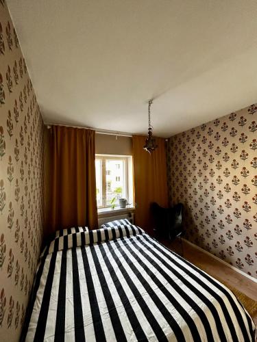 a bedroom with a striped bed with a window at The Modern Fifties in Rovaniemi